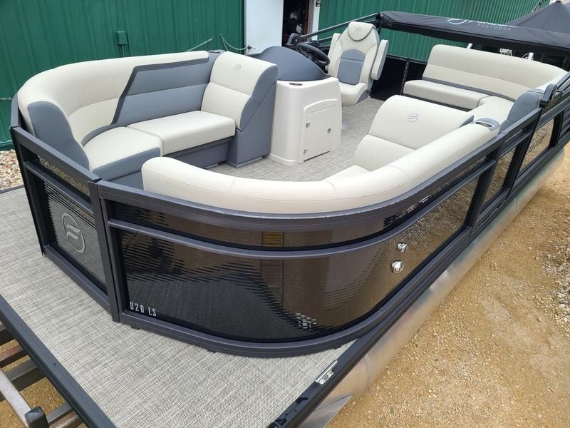 A pontoon boat with gray and white seats is sitting on a trailer.