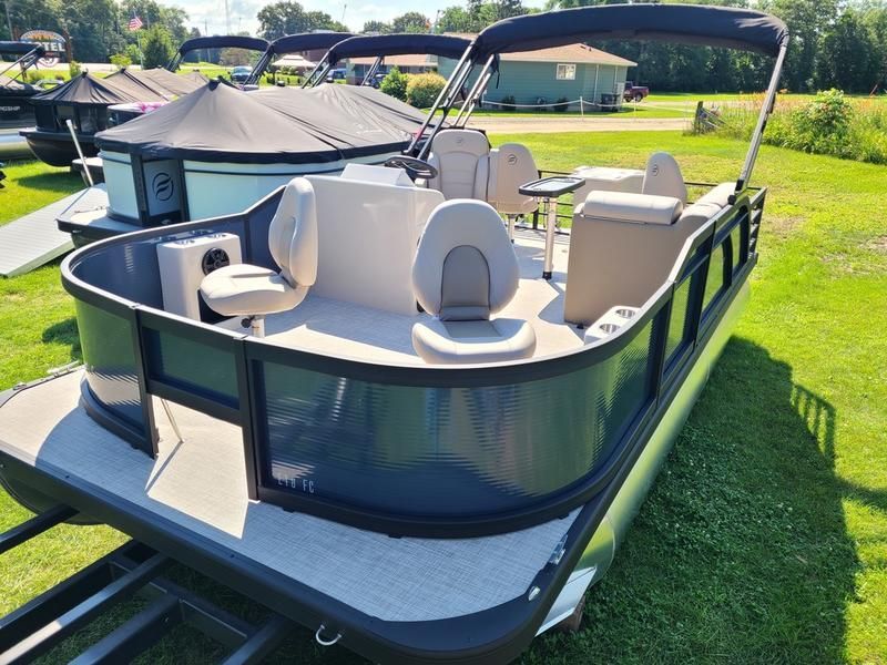 A pontoon boat is parked in a grassy field.