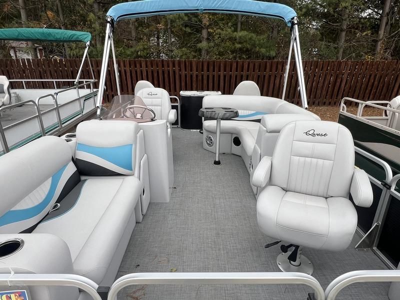 The inside of a pontoon boat with white seats and a blue canopy
