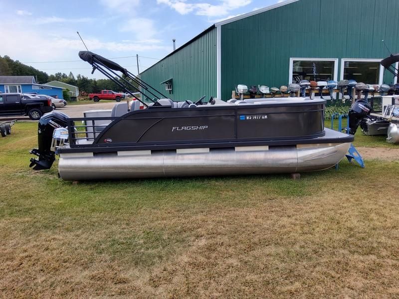 A pontoon boat is parked in front of a green building.