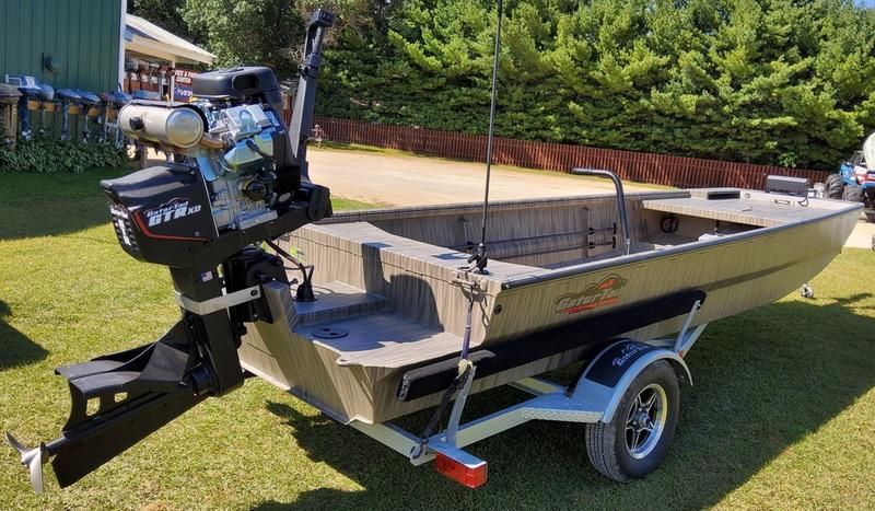 A boat with a motor attached to it is parked on a trailer.