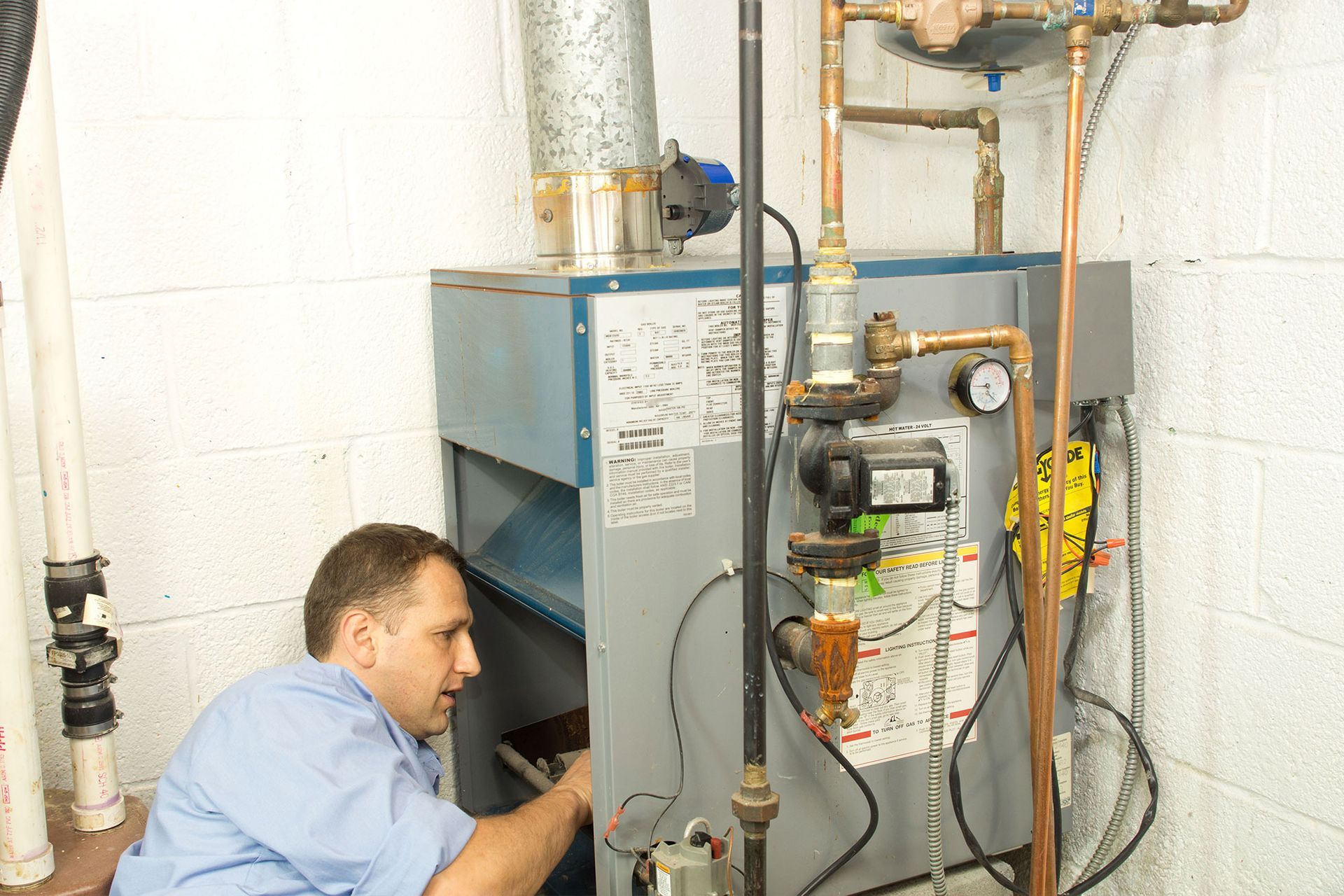 Technician inspecting a boiler and pipes in a utility room