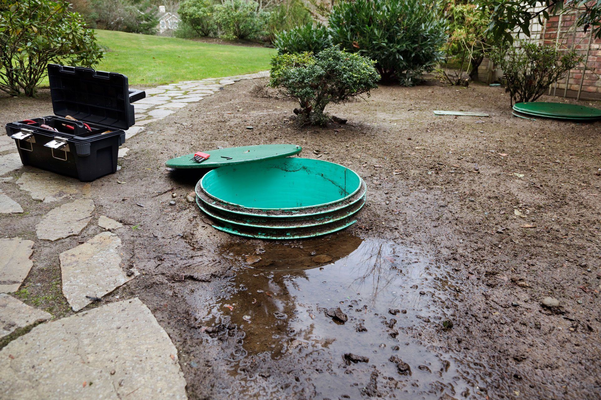 Opening the lids to investigate leaks around a septic system's tanks