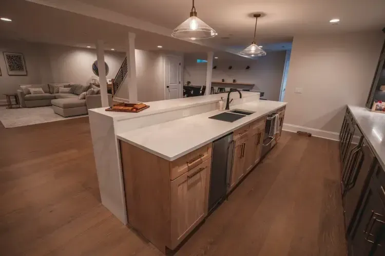 Modern open-concept kitchen with large island, white countertops, wood cabinets, and pendant lights