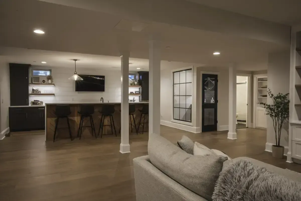 Open-concept living room and kitchen with white columns, wood floors, and modern bar seating