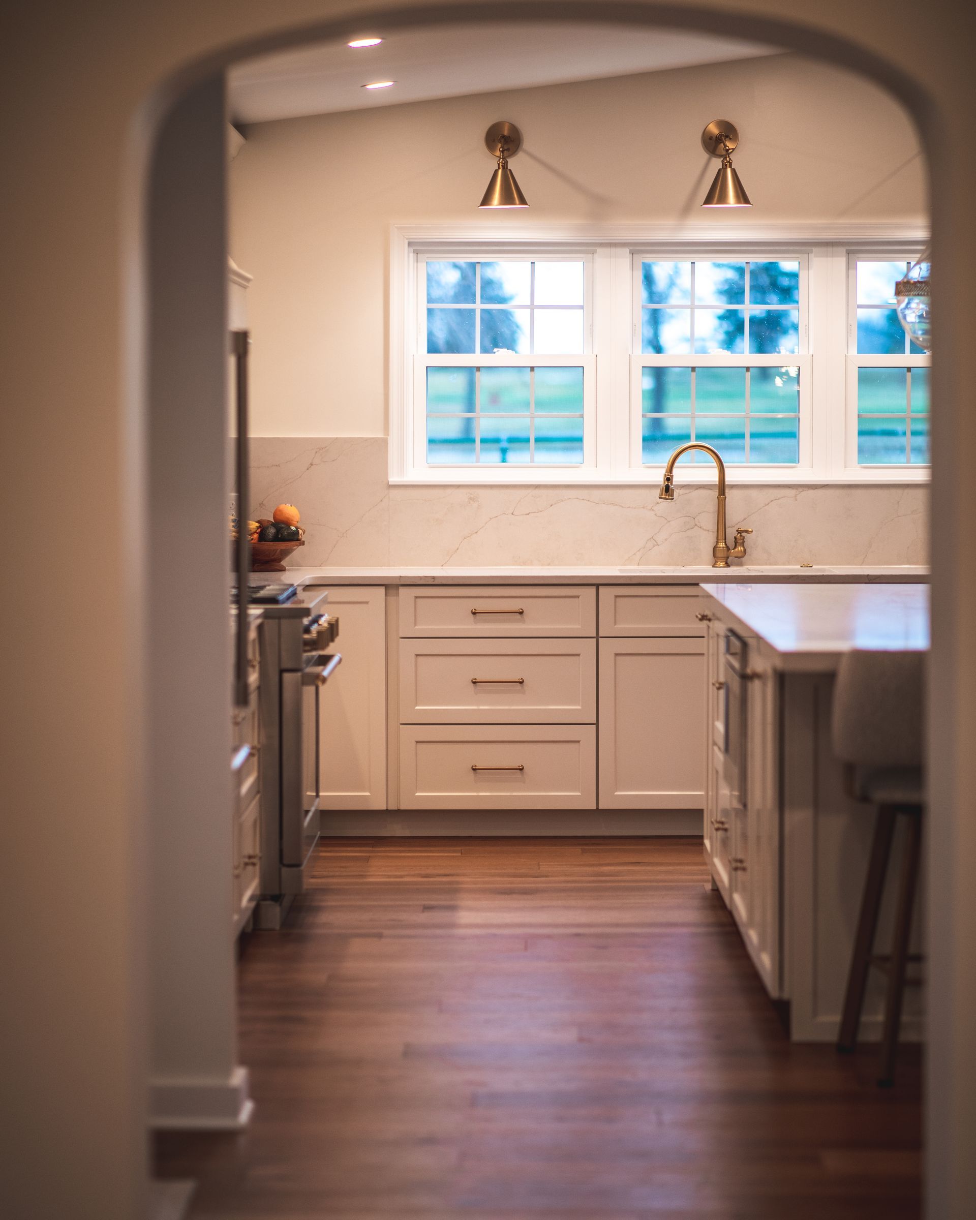 Bright kitchen with white cabinets, wooden floor, and a large window over the sink