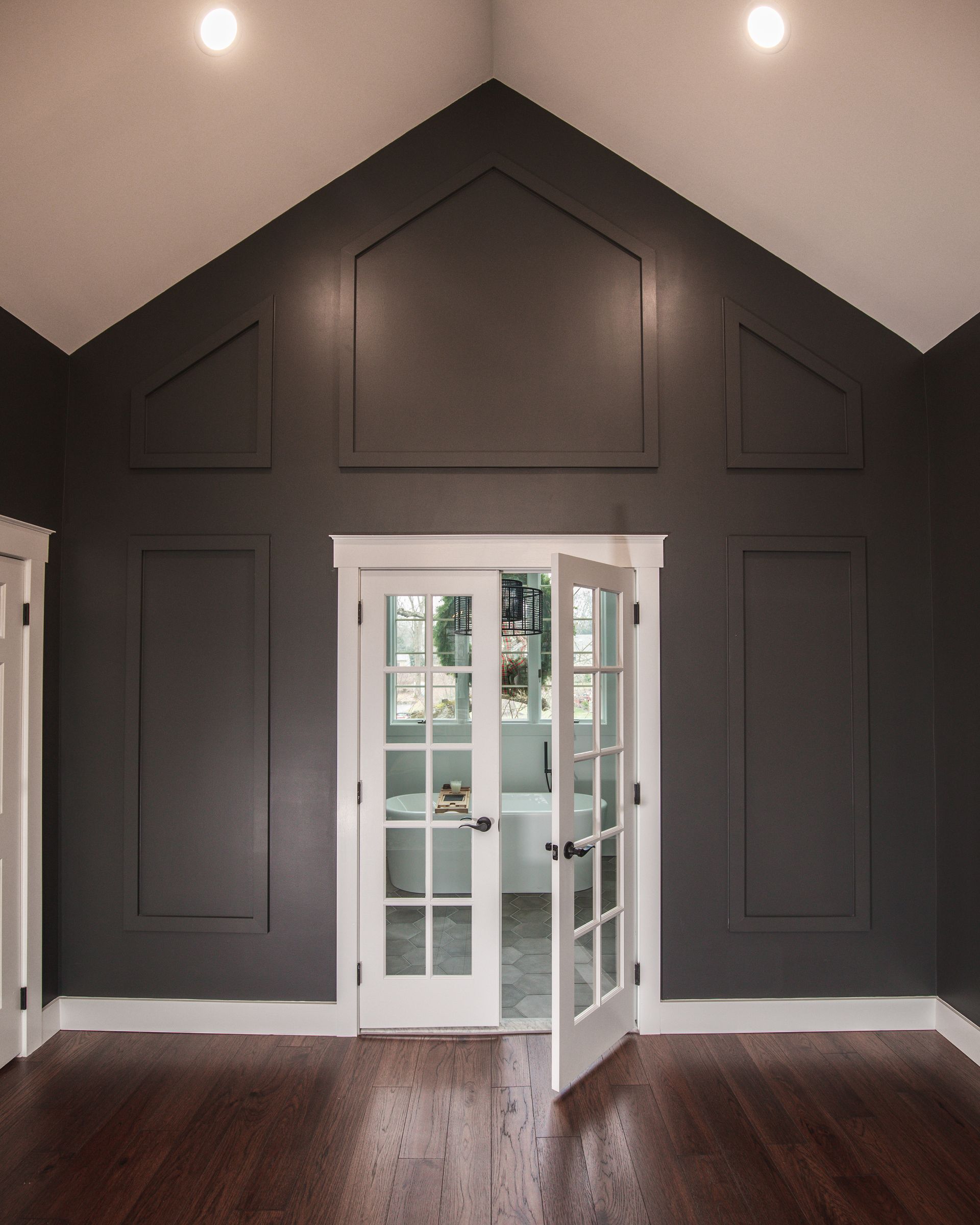 Dark gray room with vaulted ceiling, recessed lights, and French doors opening to a bright exterior.