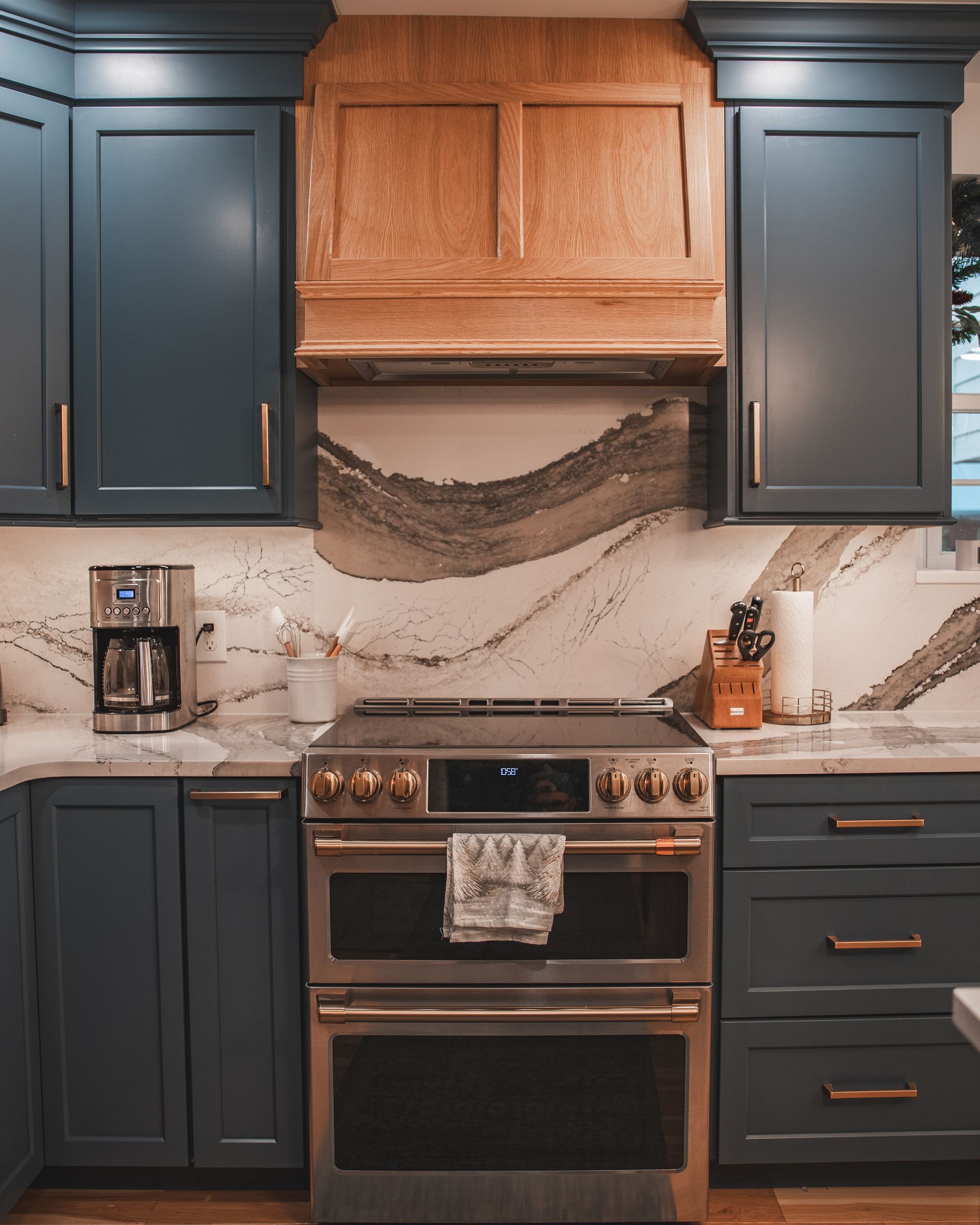 Dark blue and wood kitchen with marble backsplash, stainless stove, and wine rack