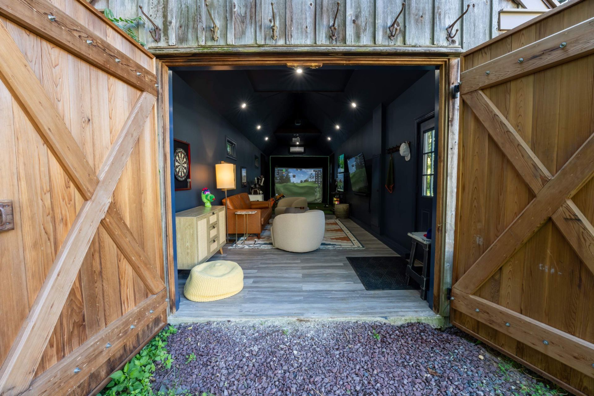 Open barn doors reveal a dim lounge with seating and a long hallway inside.