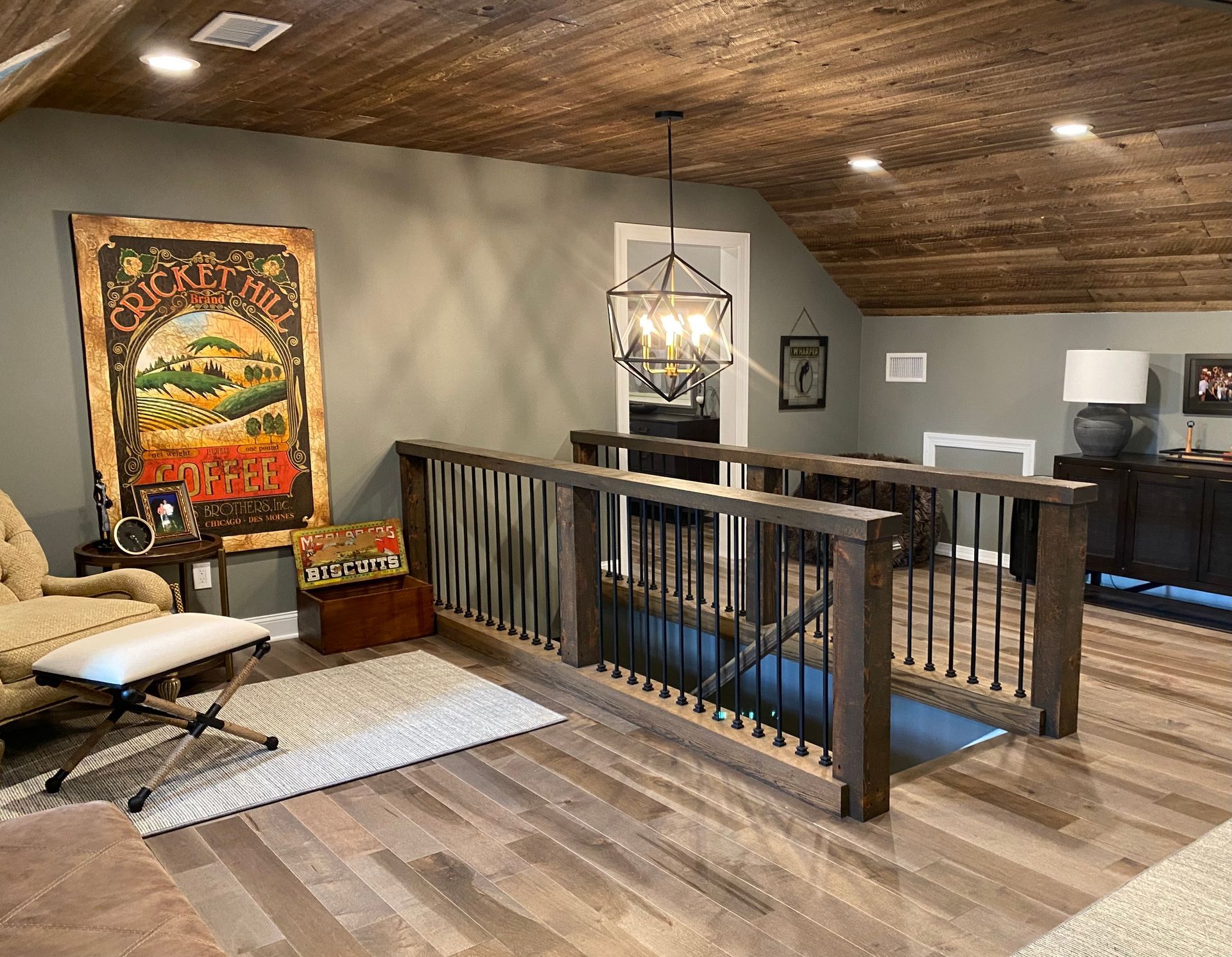 Loft with wood floors, railing, hanging lantern, and cozy chair beside colorful wall art