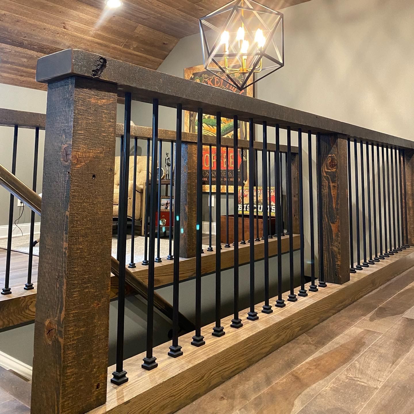 Indoor railing with black metal balusters and stone posts in a warmly lit restaurant or lobby.