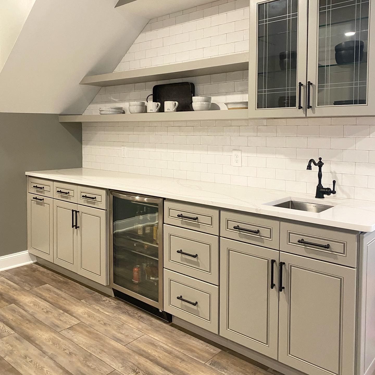 Modern kitchen with gray cabinets, white countertops, wine cooler, and open shelves under a sloped ceiling