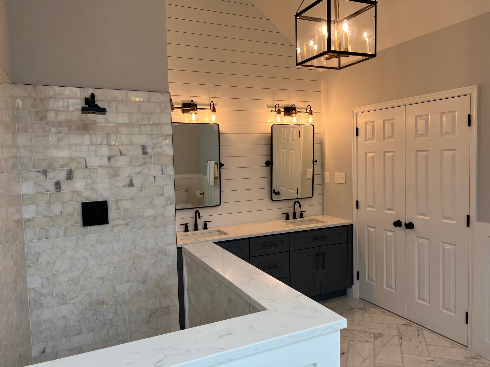 Modern bathroom with tiled shower, vanity, mirrors, and pendant lights