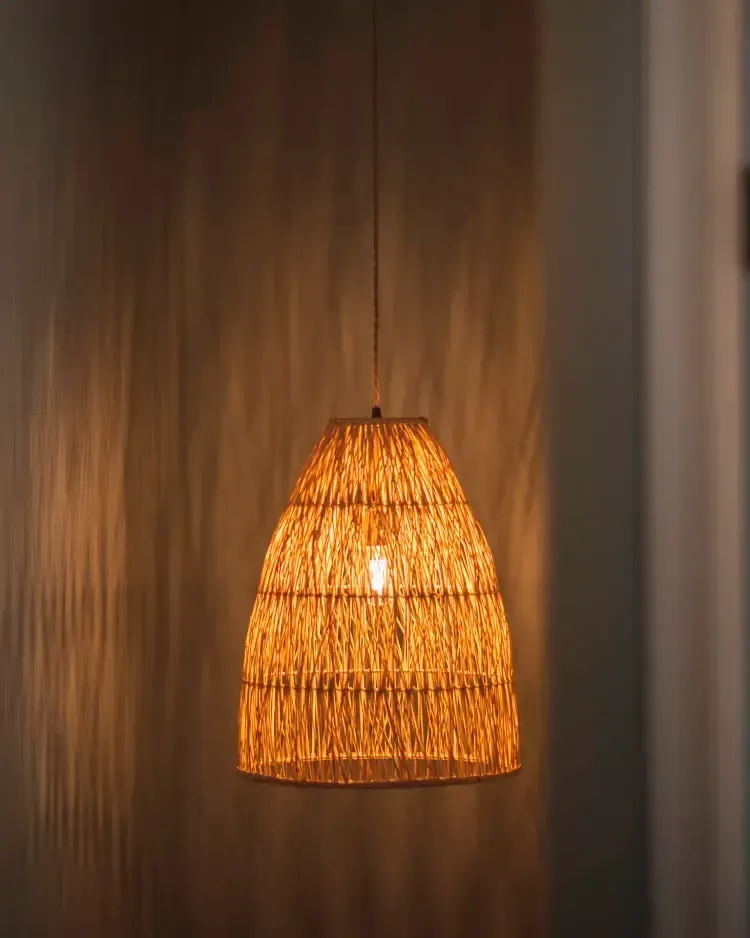 Warm woven pendant lamp glowing against a dark wooden wall