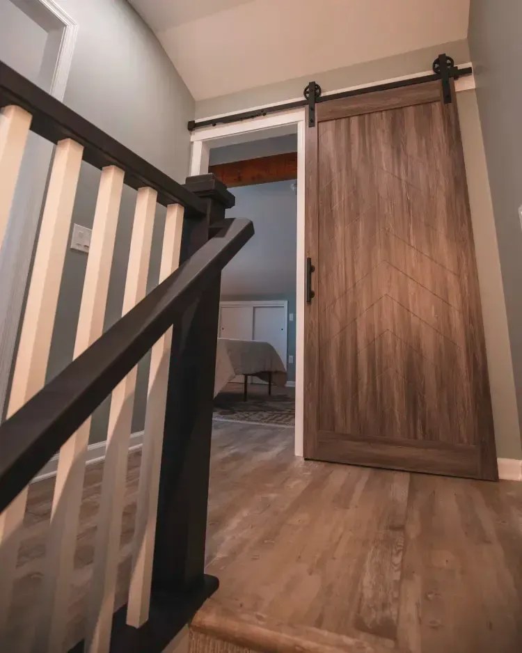 Stairway hallway with black-and-white railing and a sliding barn door opening to a room