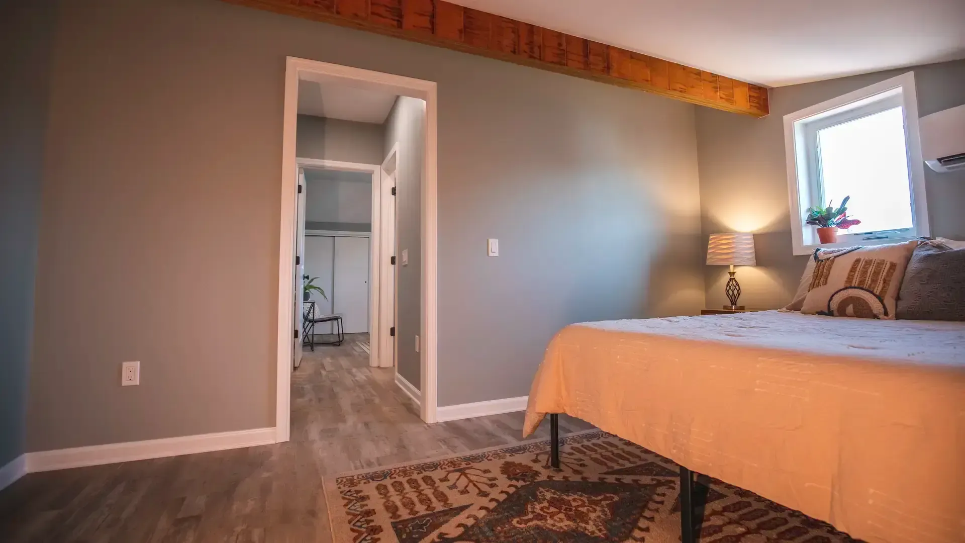 Cozy bedroom with bed, patterned rug, window, and open doorway to a bathroom or closet.
