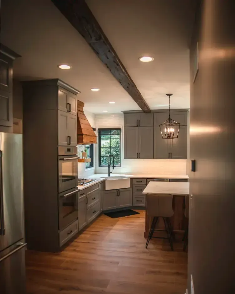 Modern kitchen with gray cabinets, wood floor, island seating, and pendant lighting