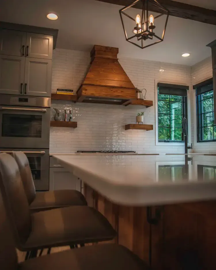 Modern kitchen with wood island, white tile backsplash, hanging lights, and built-in appliances