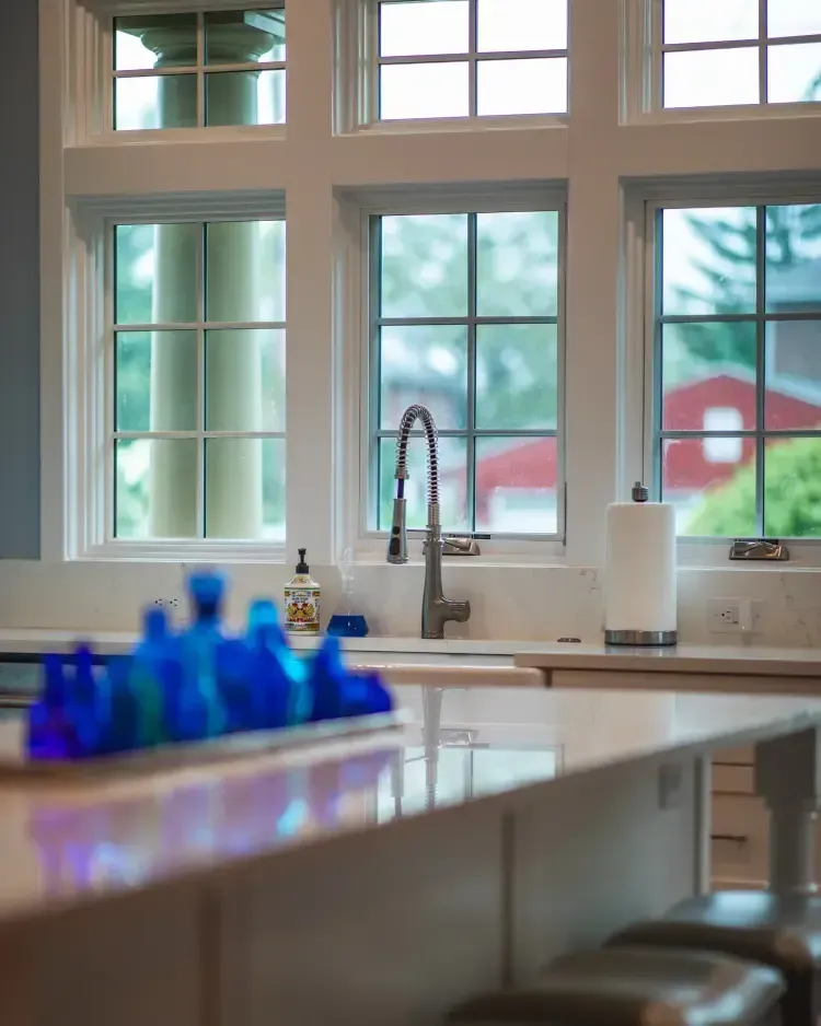Modern kitchen with a sink by large windows and blue bottles on the counter