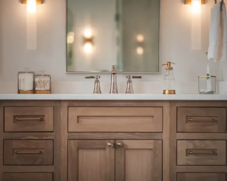Modern bathroom vanity with wood cabinets, double sink, mirror, and warm wall sconces