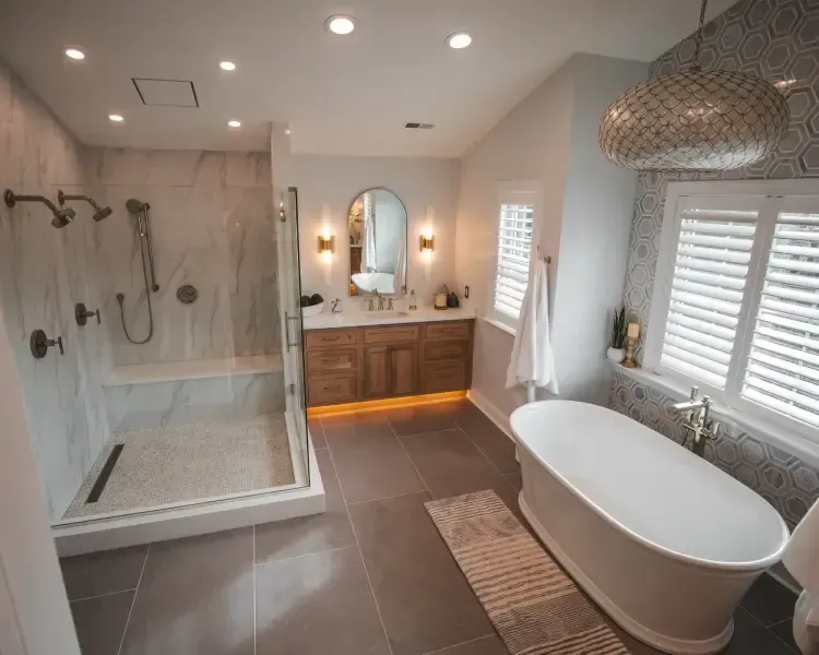 Modern bathroom with glass shower, freestanding tub, double vanity, and gray tile flooring