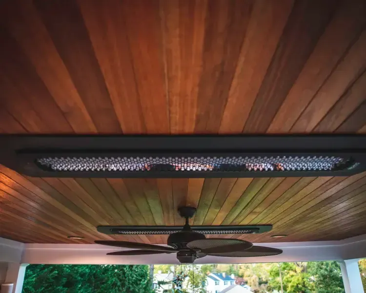 Wooden porch ceiling with two black ceiling fans and a long overhead light fixture.