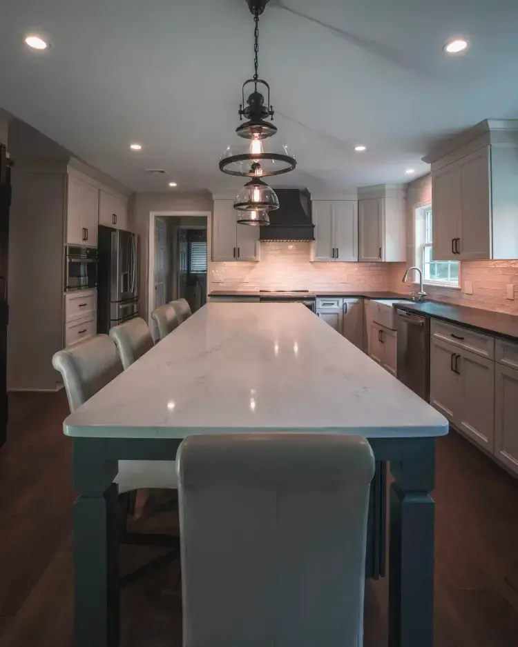 Modern kitchen with large island, pendant lights, barstools, and stainless steel appliances
