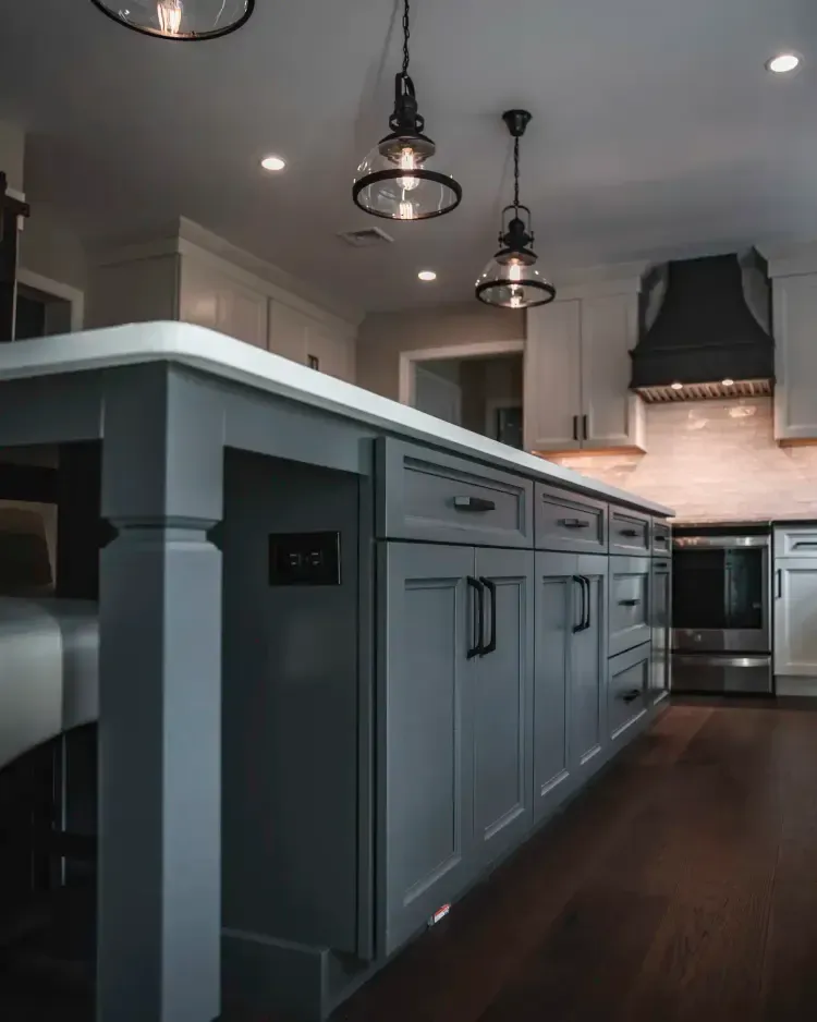 Modern gray kitchen with island, pendant lights, dark wood floor, and stainless steel appliances