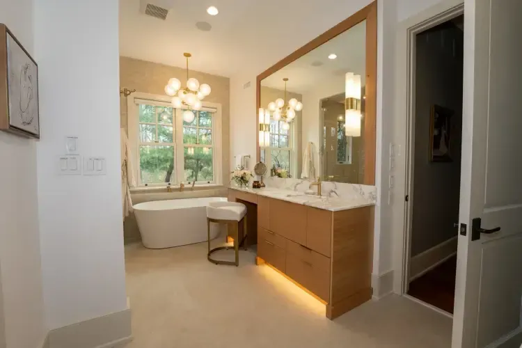 Bright bathroom with a freestanding tub, double vanity, large mirror, and window view of trees