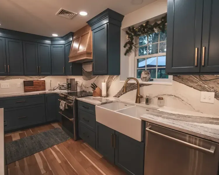 Modern kitchen with dark blue cabinets, white countertops, farmhouse sink, and stainless steel appliances