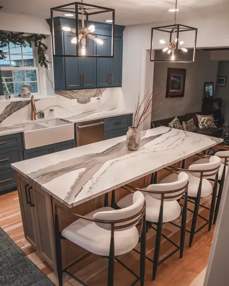 Modern kitchen with marble island, navy cabinets, pendant lights, and four stools