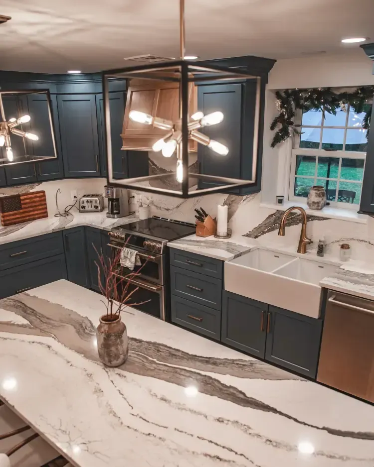 Modern kitchen with dark cabinets, white marble island, farmhouse sink, and black pendant lights