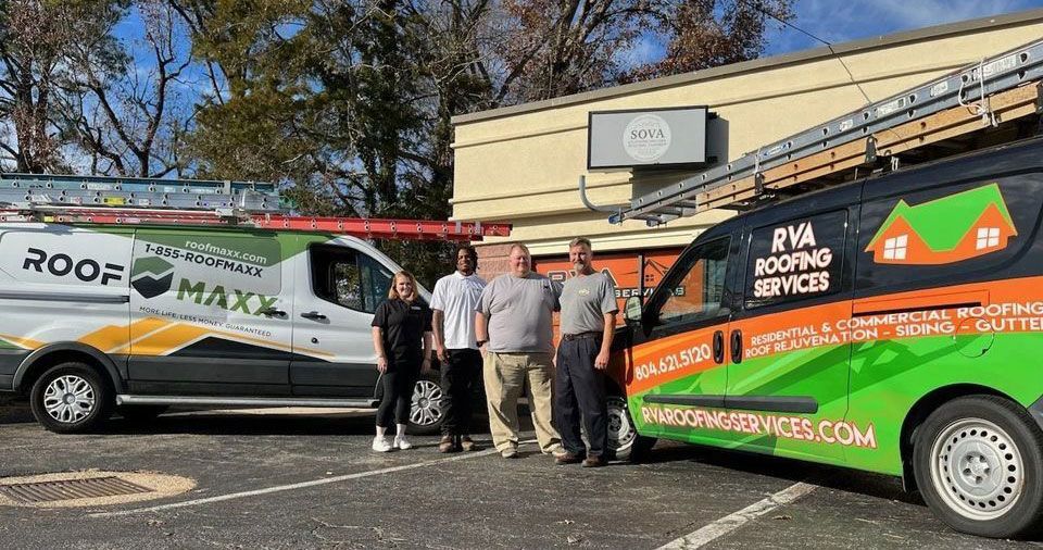 4 individuals are standing in front of two roofing vans