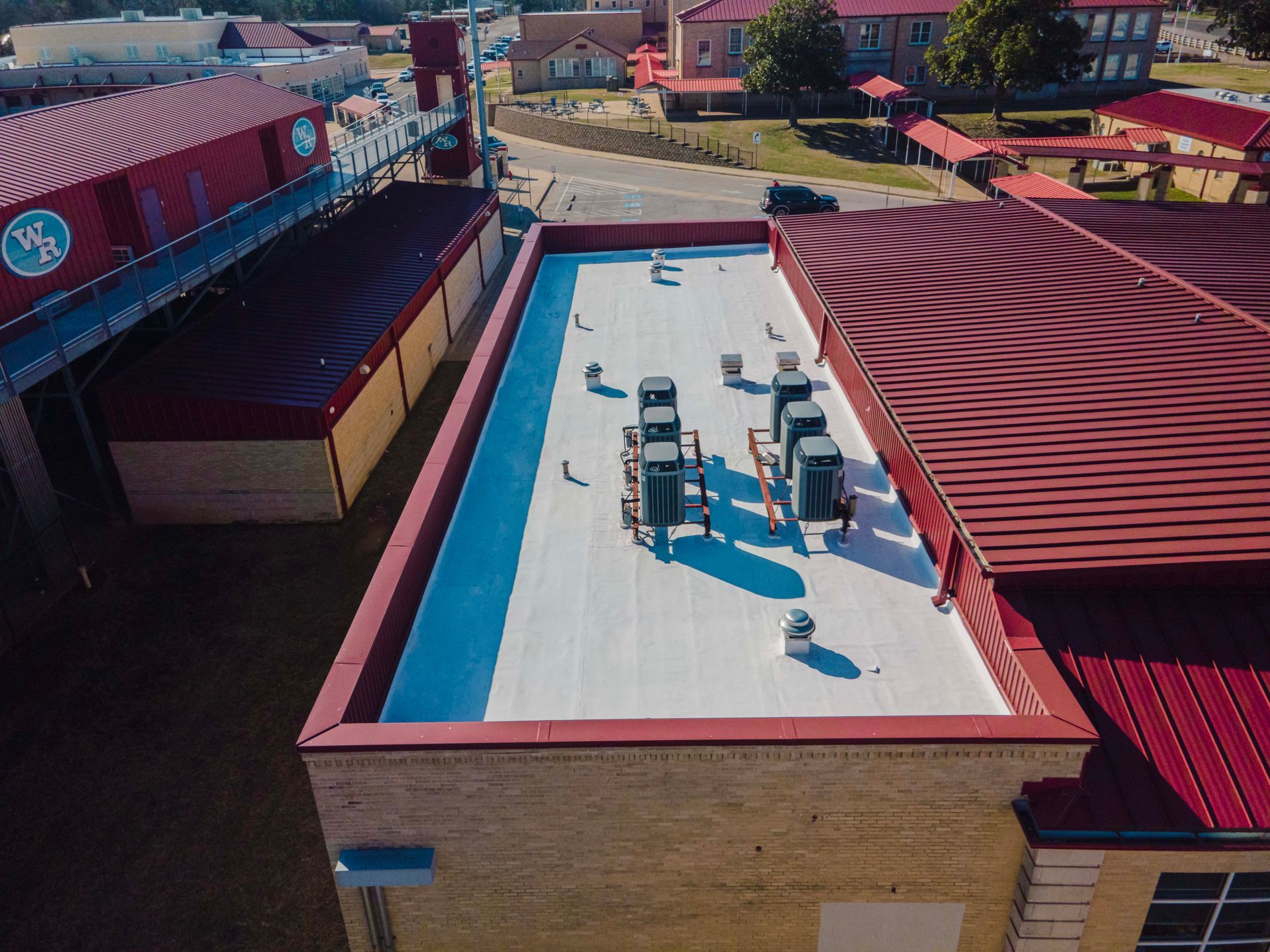 An aerial view of a large building with a white roof