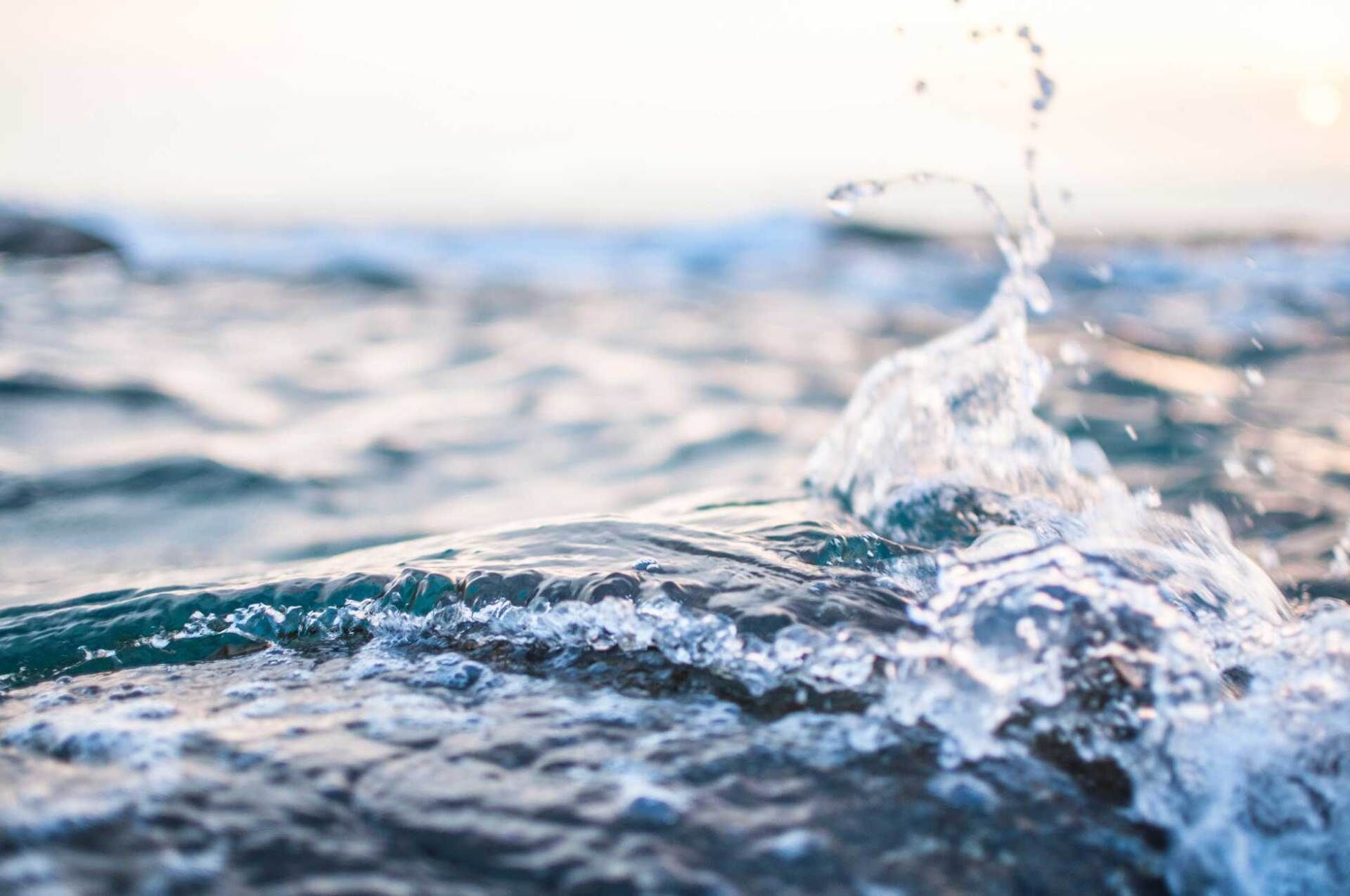 Close-up of choppy ocean water with a small splash under soft blue light