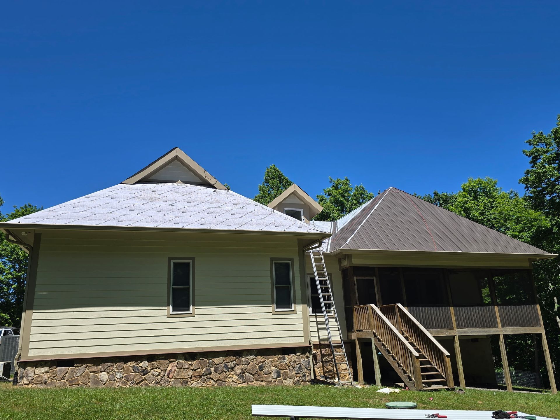 Small house with white siding and a porch, set under a bright blue sky.