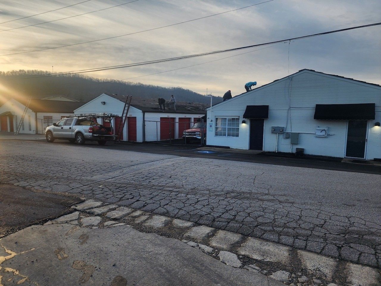 Rooftop view at sunset with equipment and hills in the background. Pink and orange clouds in the sky.