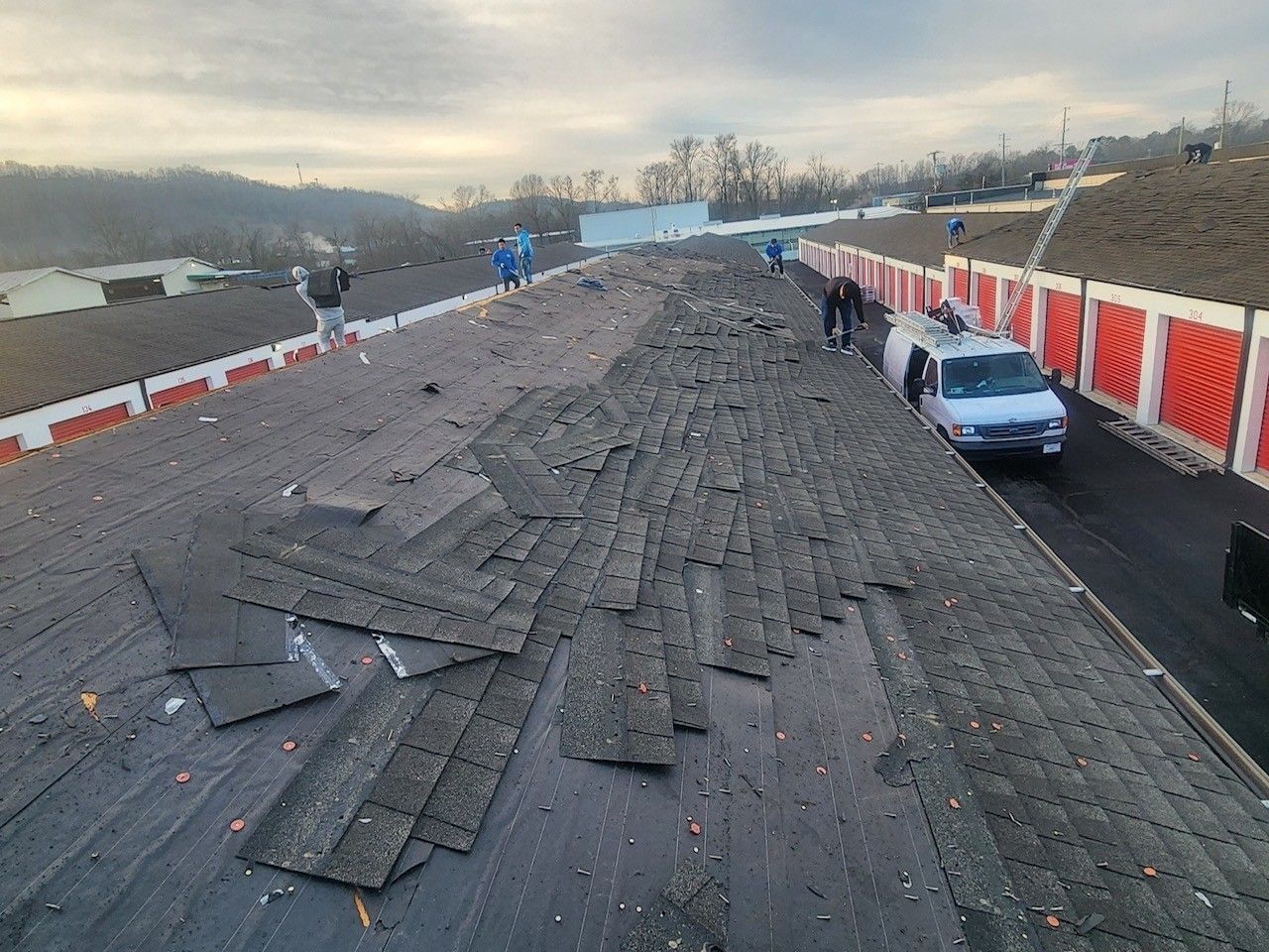Roof with white PolyShield material, equipment, and safety lines under a blue sky.