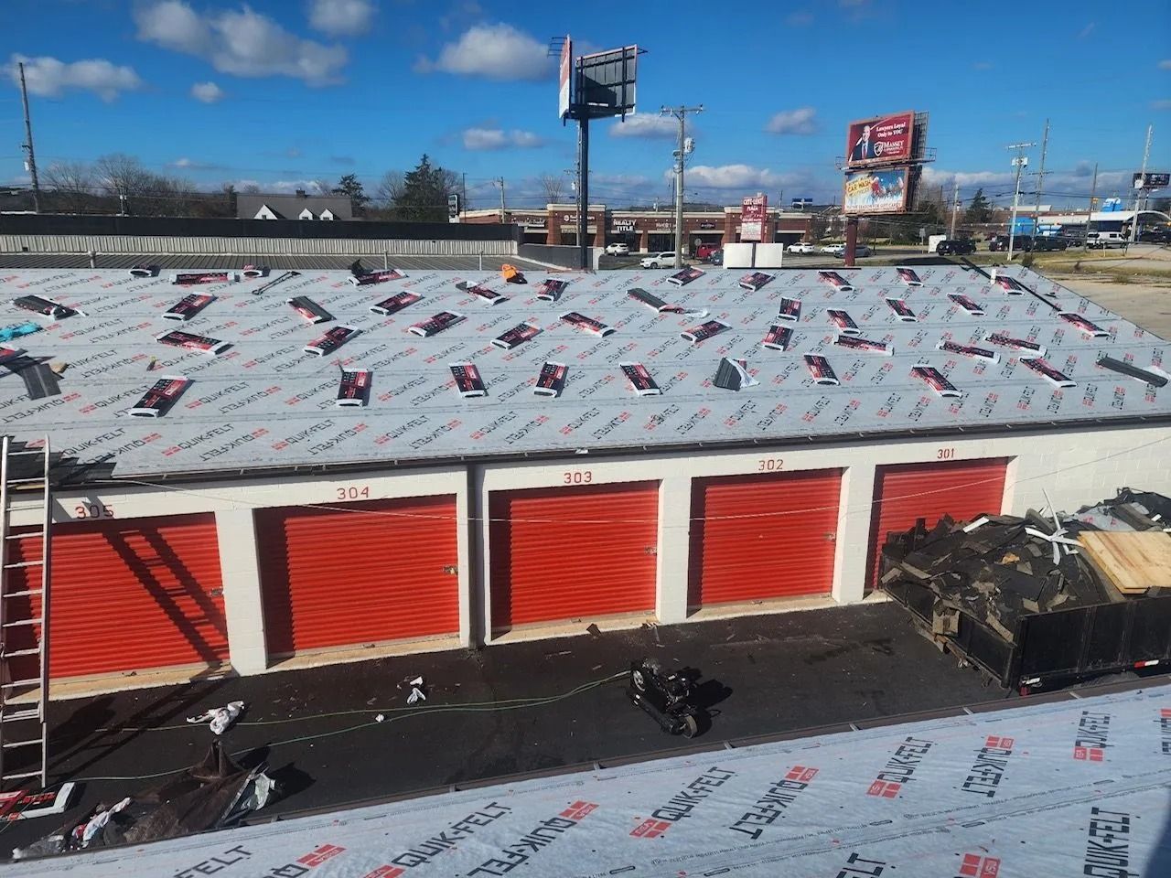 A rooftop with various industrial equipment against a backdrop of trees and a road.