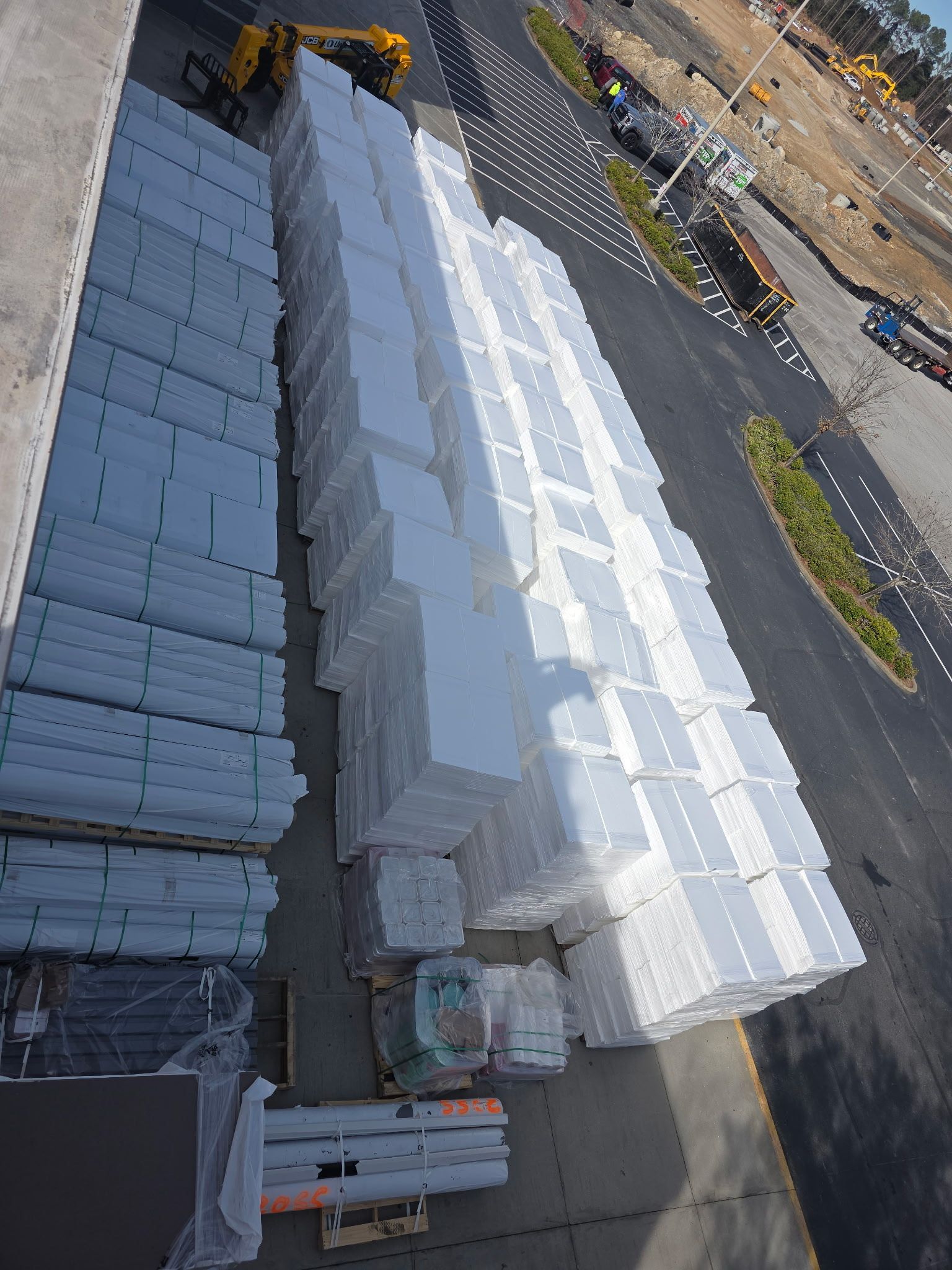Trucks parked at a large store loading materials under a blue sky.