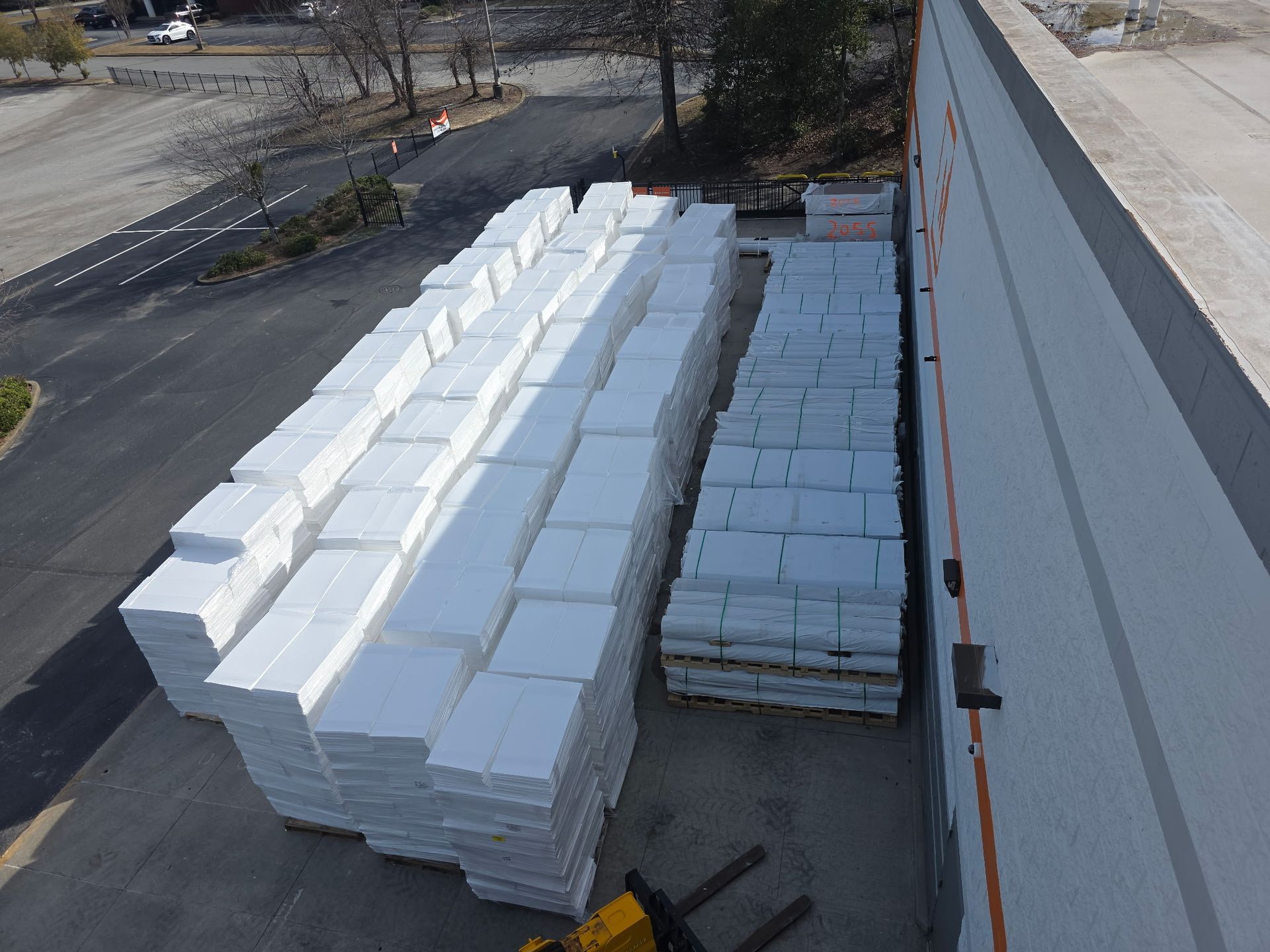 Trucks parked in a large asphalt lot under a blue sky with some clouds.