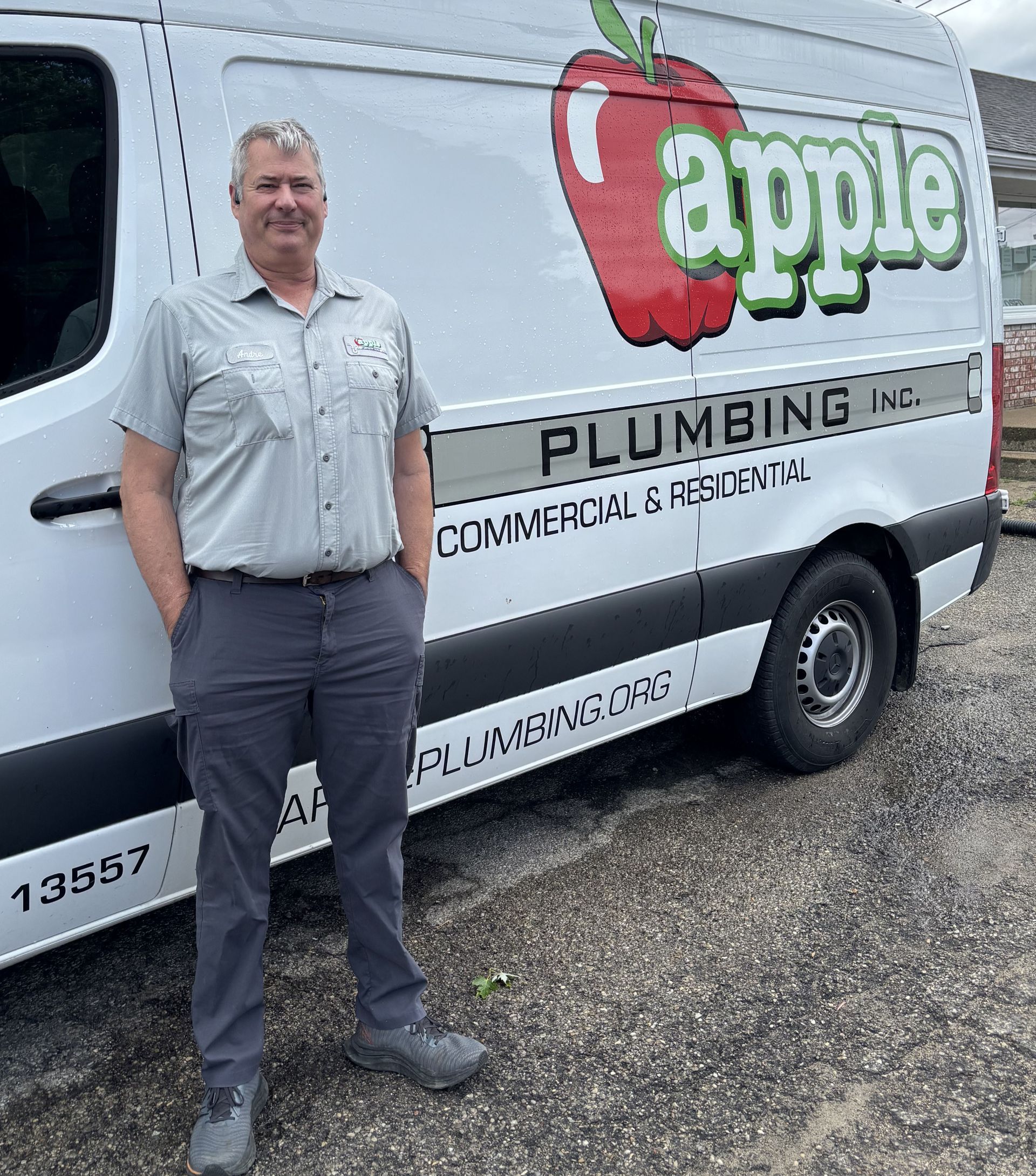 A man is standing in front of an apple plumbing van.