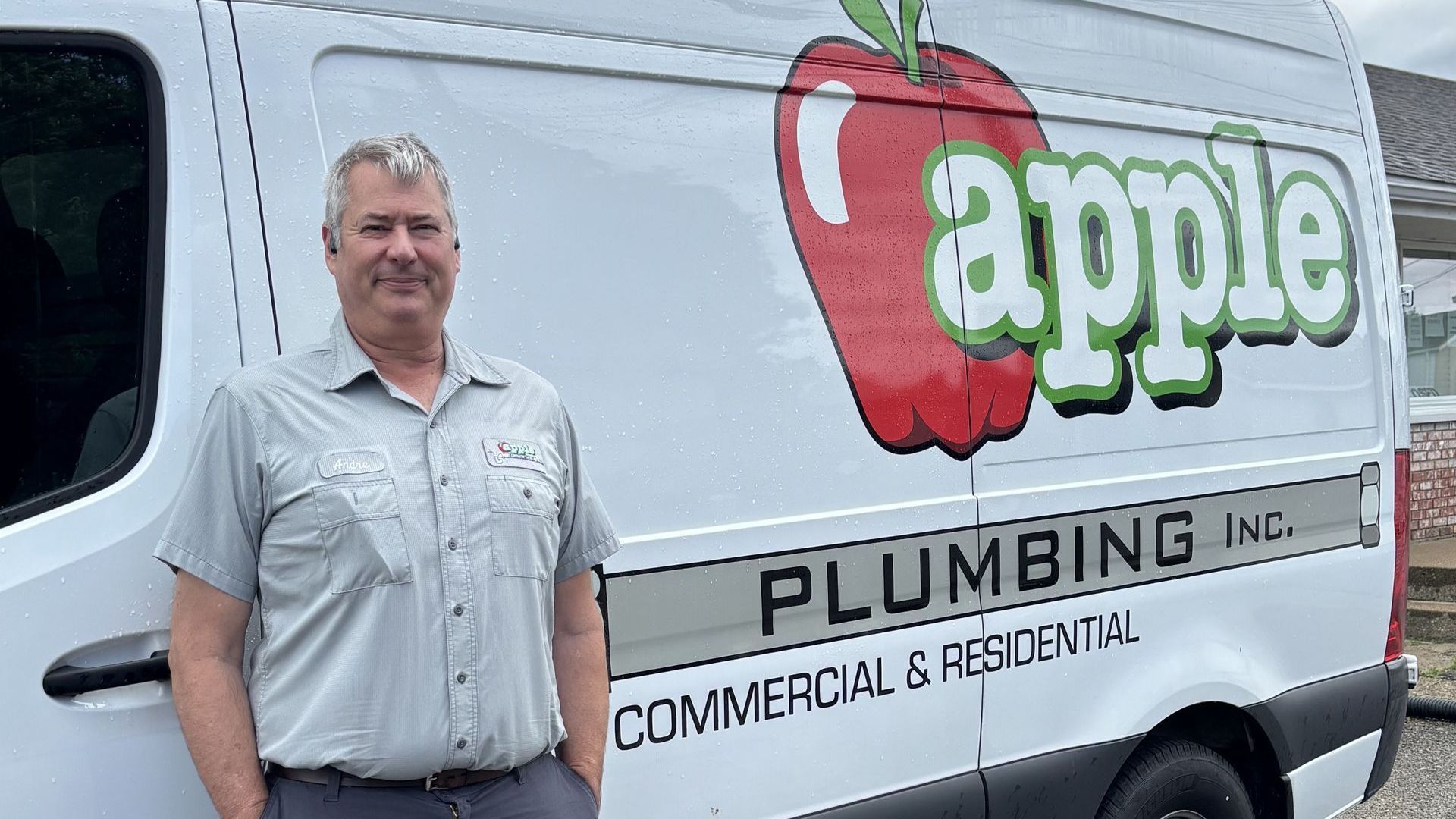 A man is standing in front of an apple plumbing van.