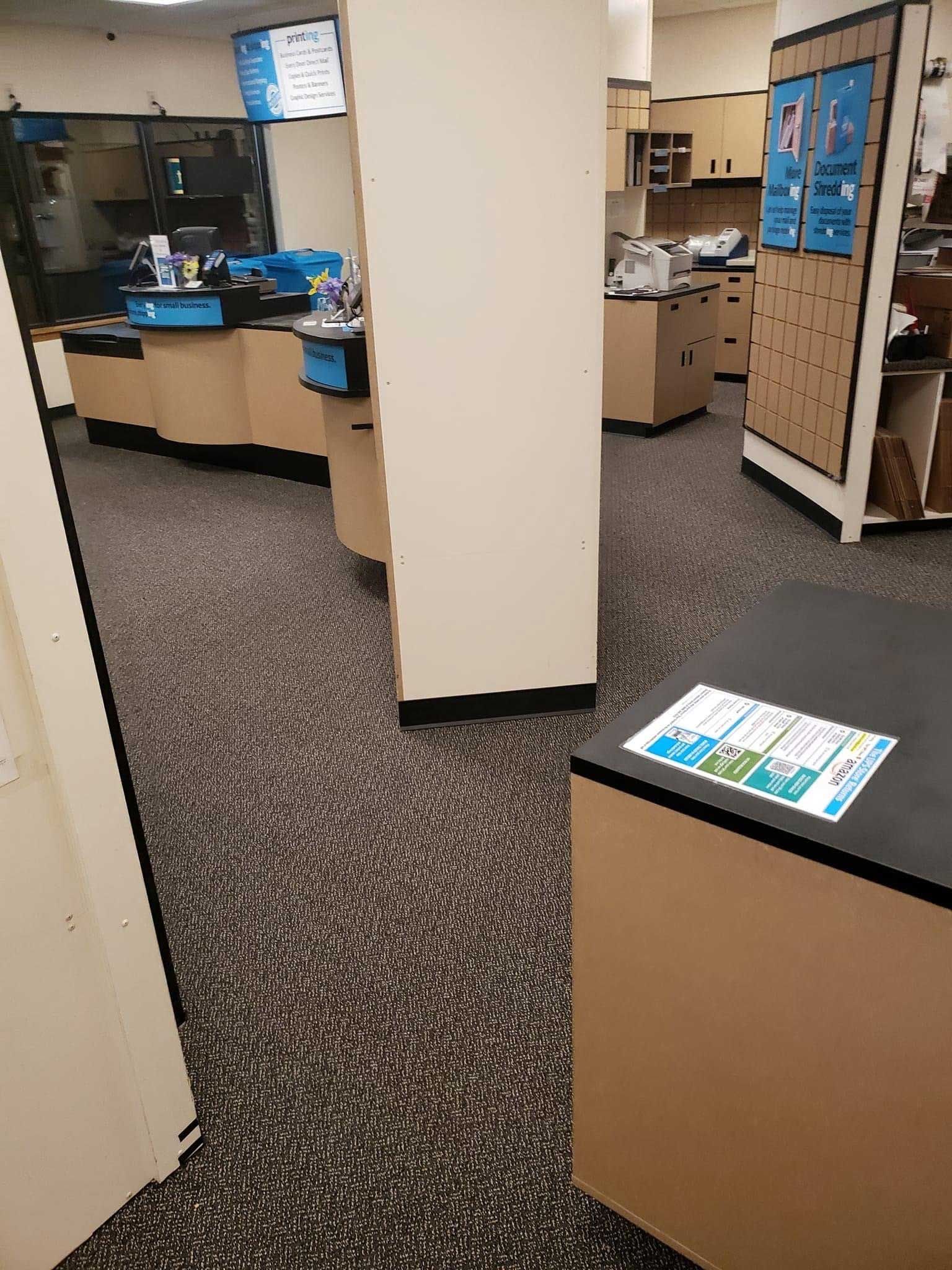 A retail store interior with counters, a support column, and carpeted floors.