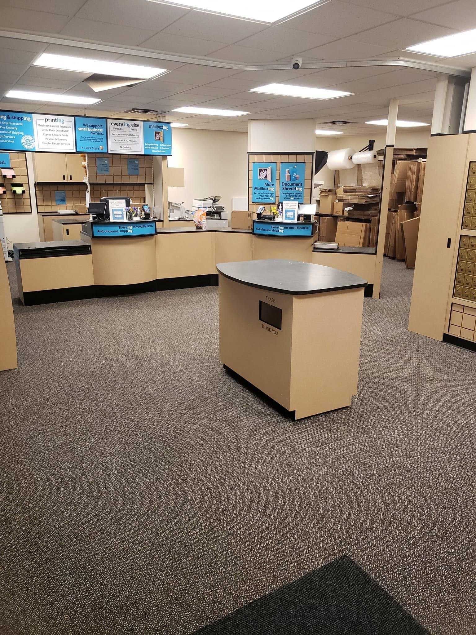 Interior of a shipping store, with counters, packaging supplies, and boxes visible. Carpeted floor.