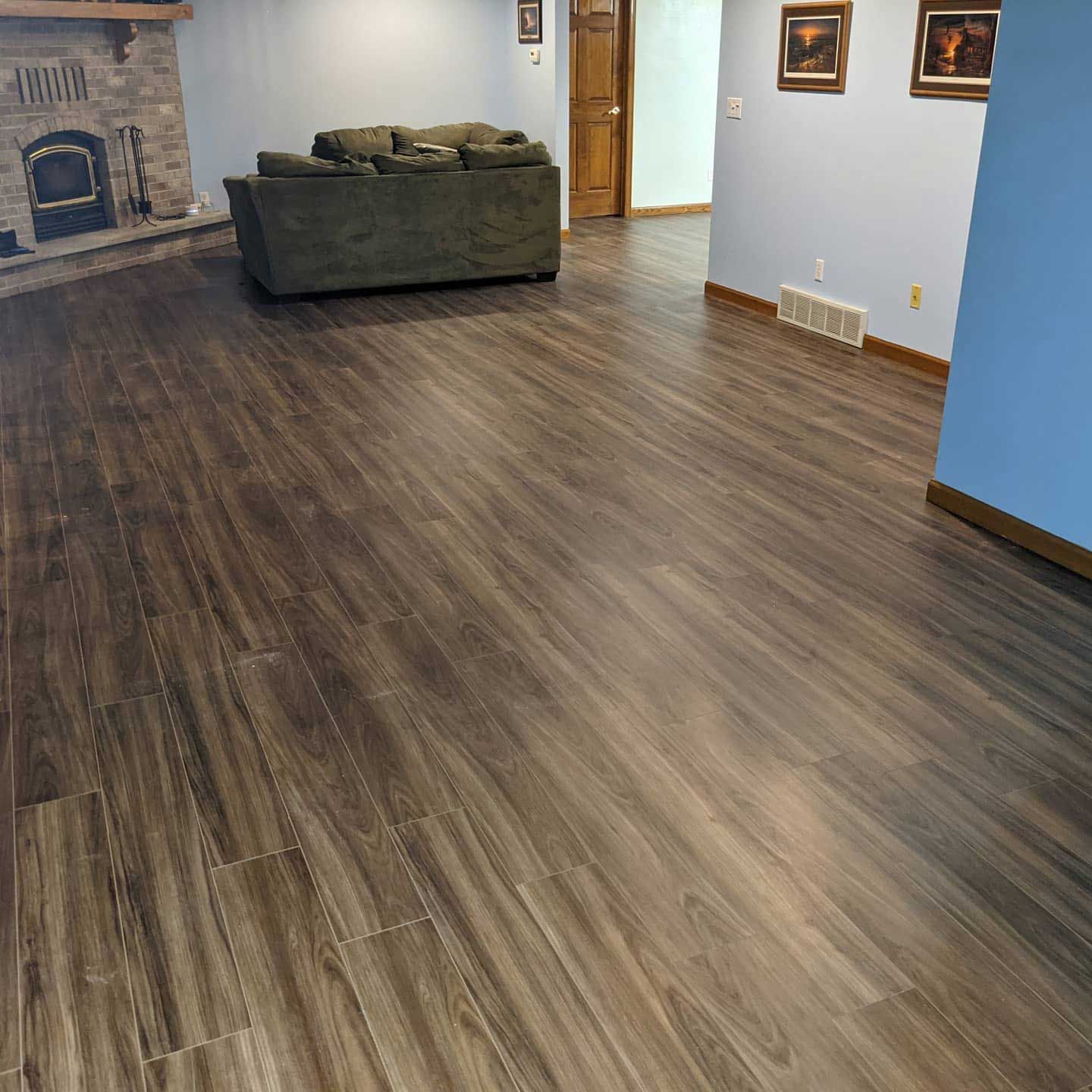 Wood-look flooring in a room with a fireplace, sofa, and light blue wall.