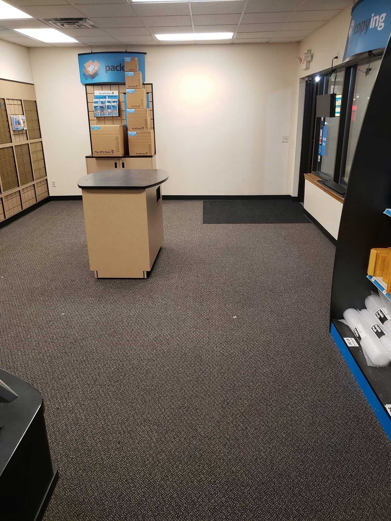 Interior of a store, with boxes stacked near a table and display racks on the right side.