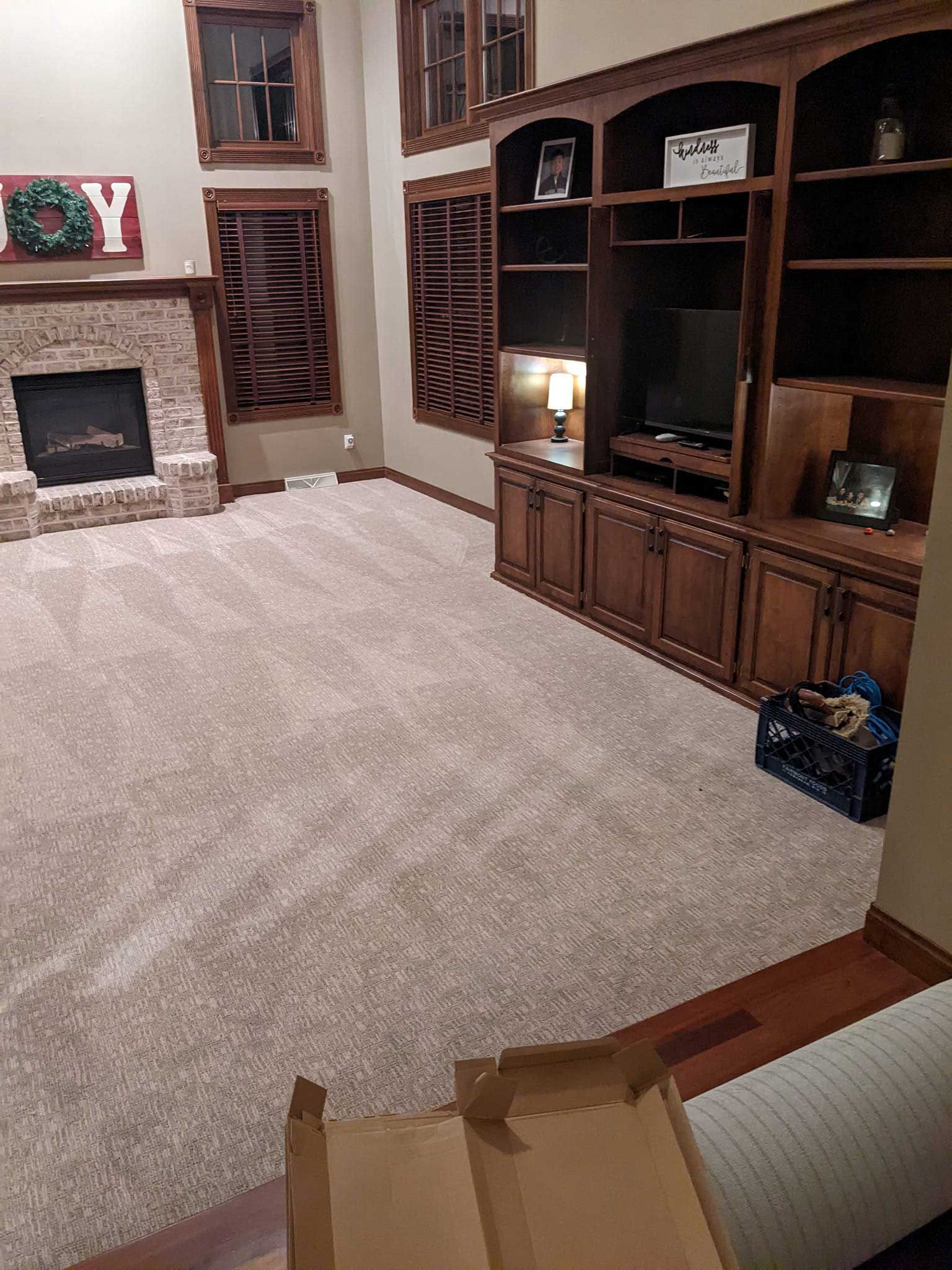 Living room with new beige carpet, a fireplace, and a built-in wooden entertainment center.