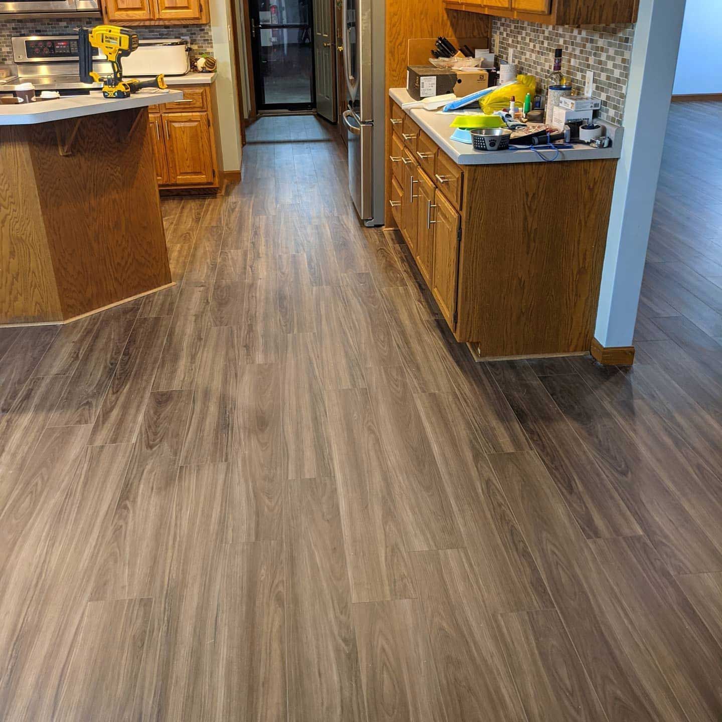 Kitchen with wood-look flooring. Brown cabinets and countertops, tools and appliances visible.