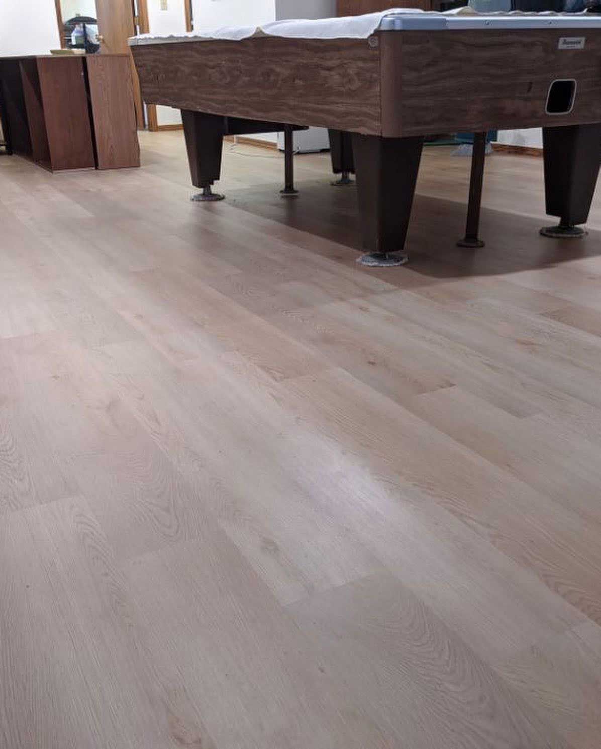 Wooden floor with a brown pool table in a room.